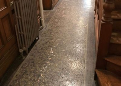 A long hallway with a radiator and staircase on the side